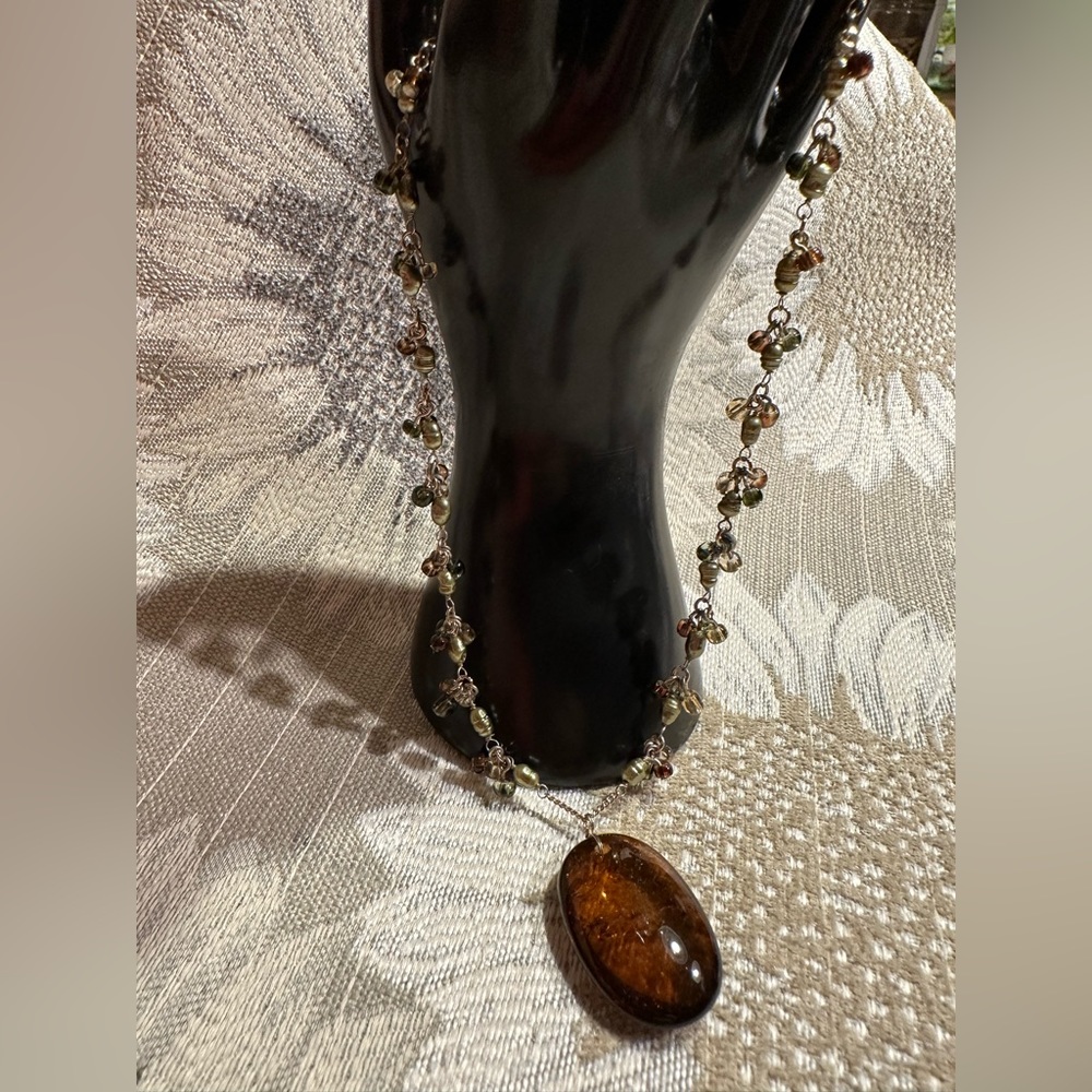 Beautiful amber stone hangs from chain with delicate clusters of small beads.